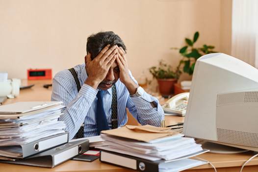 Older man with over piled desk at work - Age Discrimination
